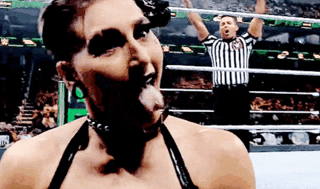 a woman is making a funny face in front of a referee in a wrestling ring .