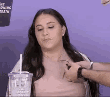 a woman is being touched by a man while holding a cup of coffee with a straw .