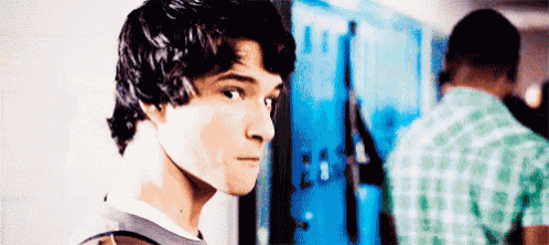 a young man is standing in front of a locker looking at the camera .