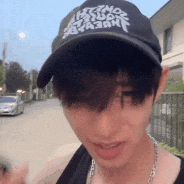 a man wearing a hat that says ' a ' on it is standing on a street
