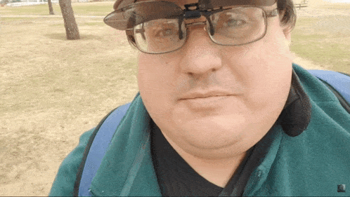 a man wearing glasses and a hat with a clip on visor