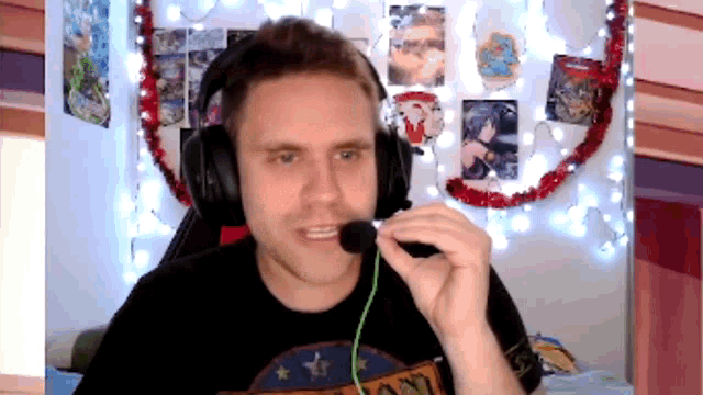 a man wearing headphones is talking into a microphone in front of a wall with pictures on it
