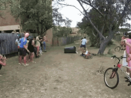 a group of people standing on a dirt road including a bicycle