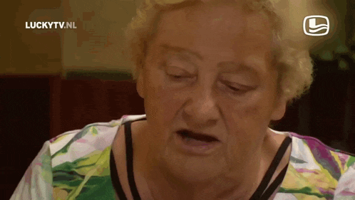 an older woman is sitting in front of a luckytv.nl sign