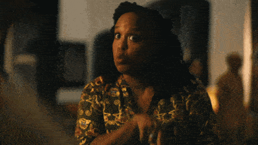 a woman with dreadlocks is wearing a green shirt with a pattern on it