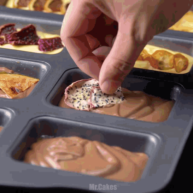a person 's hand is reaching into a tray of food with the word mr.cakes on the bottom