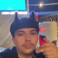 a man wearing a cat ear hat is taking a picture of himself