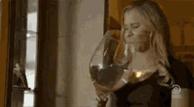 a woman is drinking a glass of wine from a large glass .