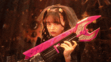 a girl with a veil on her head is holding a pink and white toy gun