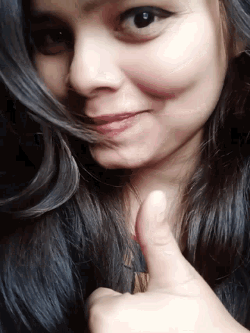 a close up of a woman 's face with a thumbs up