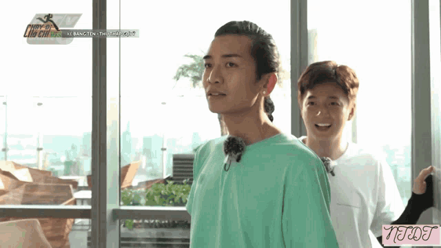 a man in a green shirt stands next to another man