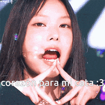 a close up of a woman making a heart shape with her hands and the words corazon para mi cata below her
