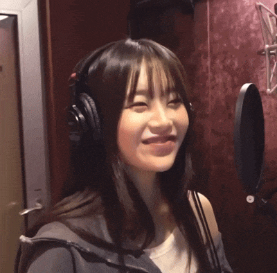 a woman wearing headphones is smiling and looking at the camera