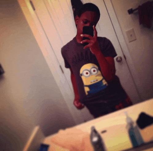 a person taking a selfie in front of a mirror wearing a shirt with a minion on it