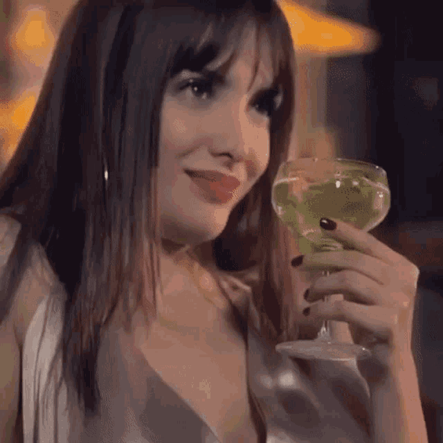 a woman in a dress is holding a glass of wine .