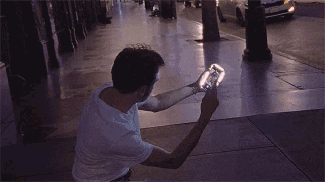 a man is taking a picture of himself on a sidewalk with a car in the background