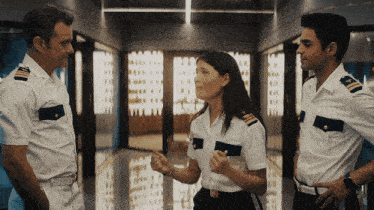 two men and a woman in military uniforms are standing in a hallway