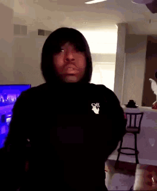 a man is wearing a black sweater with a white logo on the front .
