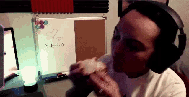 a man wearing headphones is eating a sandwich in front of a whiteboard that says heyther g