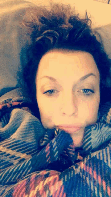 a woman is wrapped in a plaid blanket