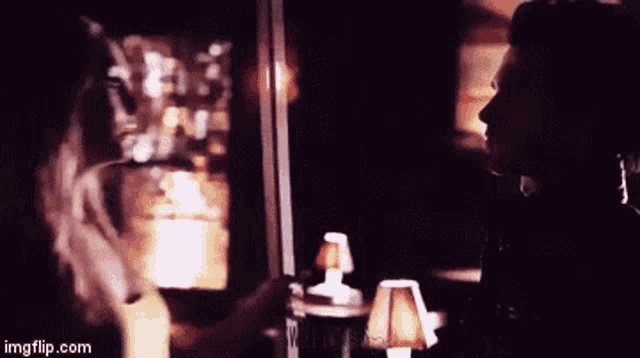 a man and a woman are looking at each other in a dark room ..