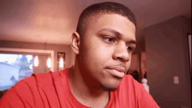 a man in a red t-shirt looks at the camera