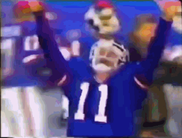 a football player with the number 11 on his jersey holds his arms in the air