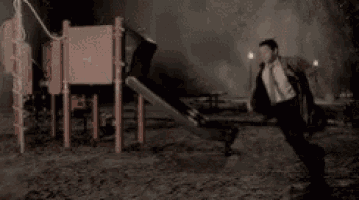 a man with a backpack is running in front of a playground .