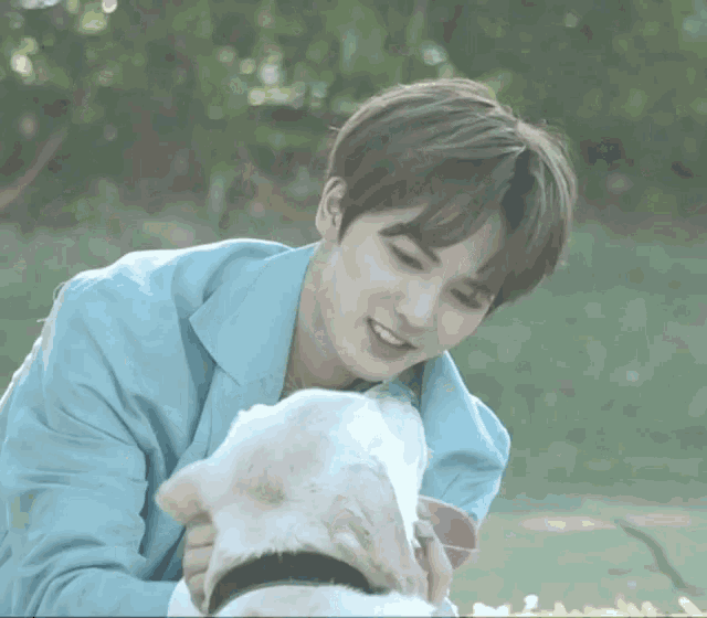 a young man is petting a small white dog .