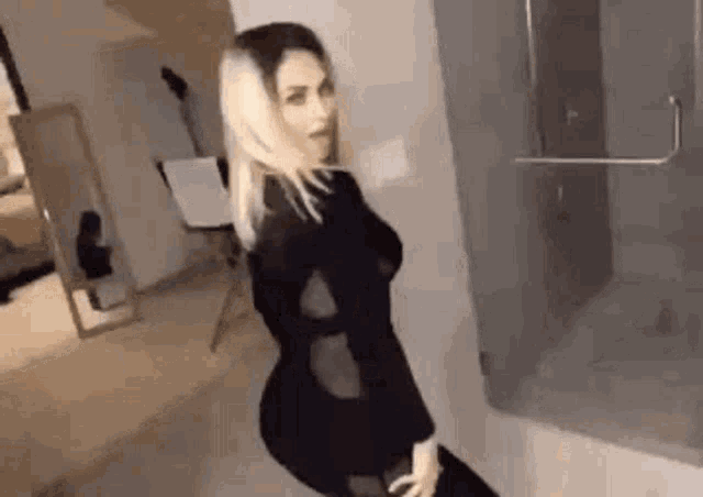 a woman is standing in front of a mirror in a room .