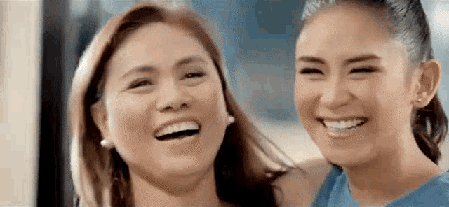 two women are smiling at each other and laughing together .