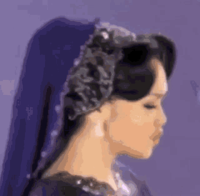 a woman wearing a purple dress and a blue head scarf is standing in front of a purple background .