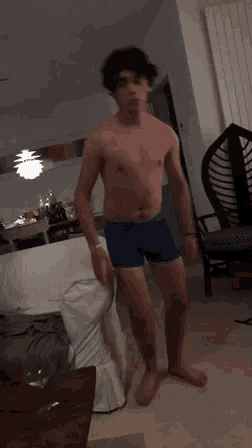 a shirtless man in blue boxer shorts is standing in a living room