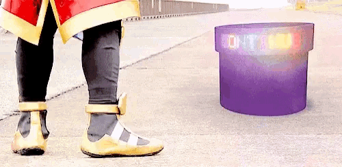 a person in a superhero costume is standing next to a purple container on the ground .