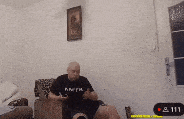 a man sitting on a couch wearing a shirt that says nagga on it
