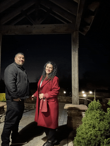a man and a woman are standing under a gazebo at night