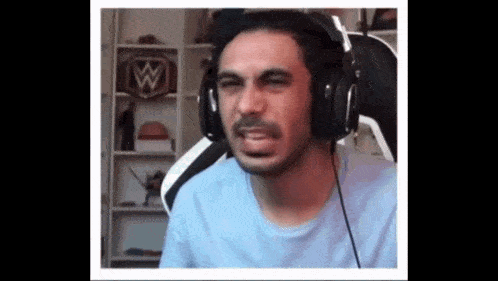 a man is wearing headphones and making a funny face while sitting in a chair .