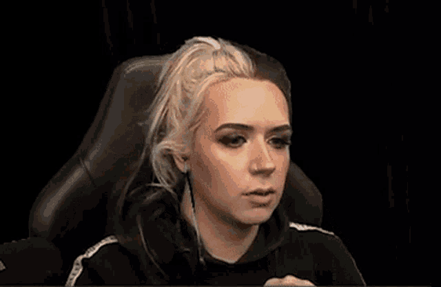 a woman is sitting in a chair with headphones on and making a funny face .