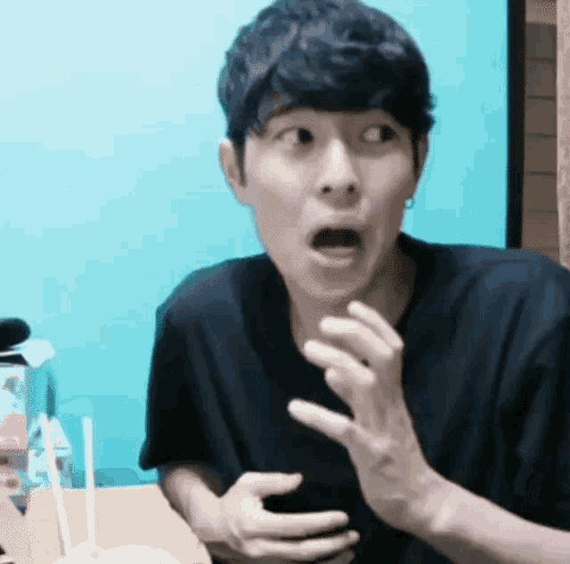 a man is making a surprised face while holding a cell phone .