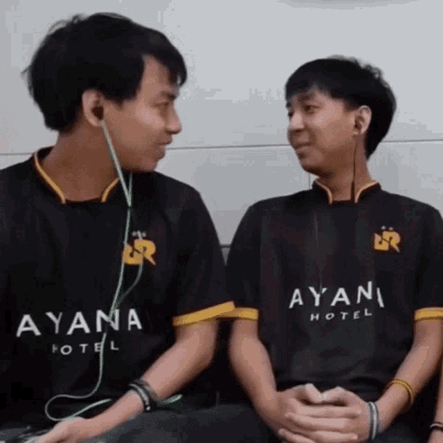 two boys wearing ayana hotel shirts are sitting next to each other