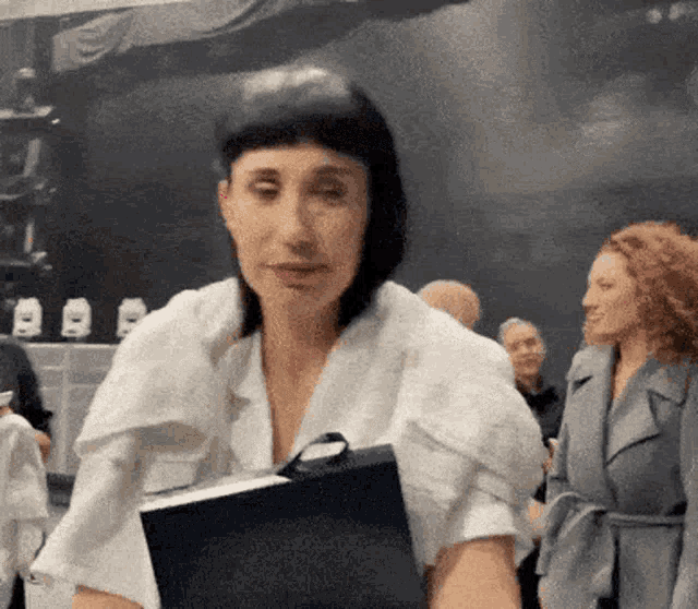 a woman in a white shirt holds a black book