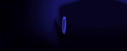 a green shield is glowing in the dark against a dark blue background .