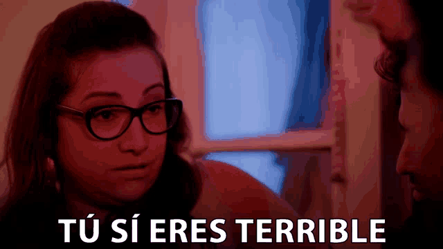a woman wearing glasses is looking at a man with the words " tu si eres terrible " behind her