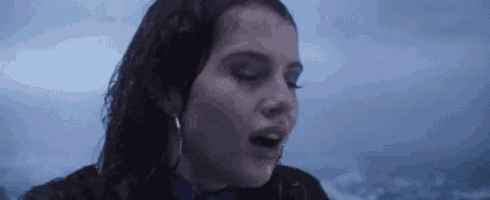 a woman is standing in the rain with her mouth open and her hair wet .
