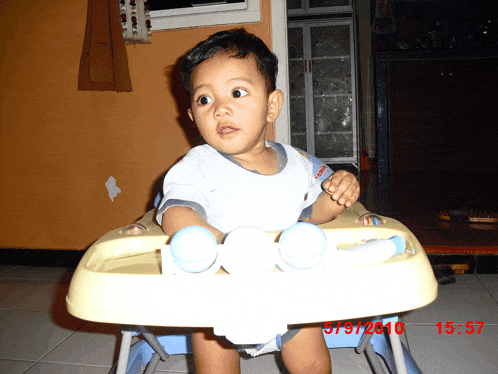 a baby is sitting in a high chair with the date 5/9/2010 on the bottom