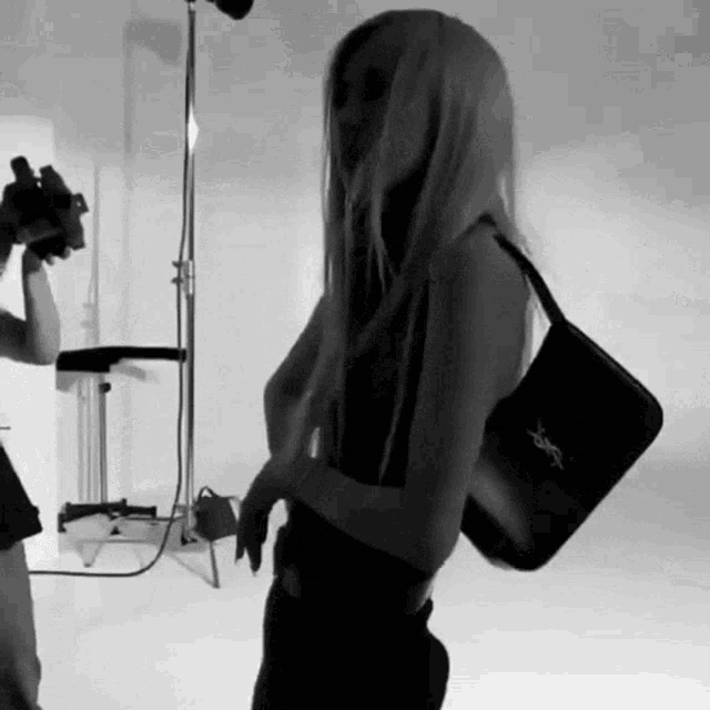 a black and white photo of a woman holding a bag .