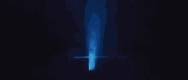 a cross is lit up in the dark with a blue light coming out of it