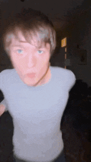 a young man in a white t-shirt is making a funny face .