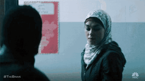 a woman in a hijab is standing next to a man in a black jacket .