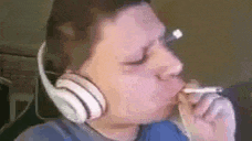 a man wearing headphones is smoking a cigarette while looking at something .